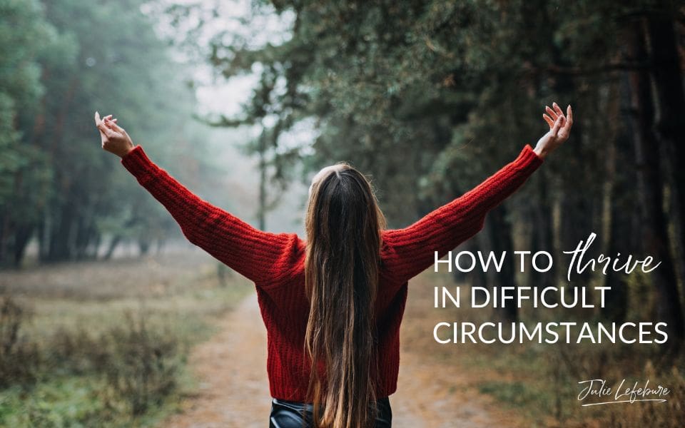 How to Thrive in Difficult Circumstances | woman in red sweater standing on road with arms held up in the air