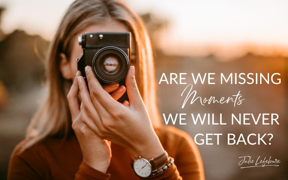 Are We Missing Moments We Will Never Get Back | woman in rust-colored sweater looking through camera lens, focusing camera and facing forward towards camera